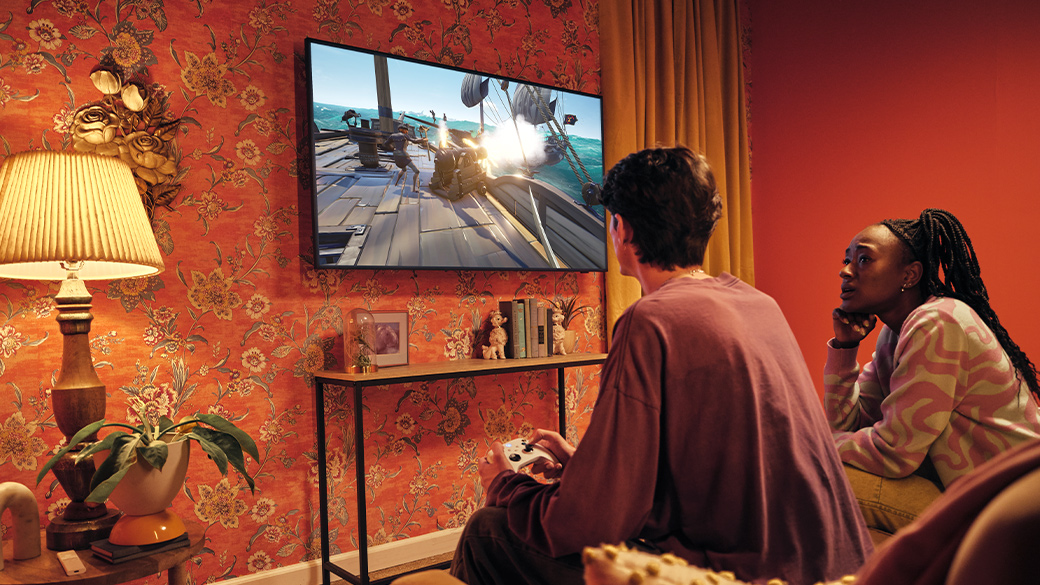 Dwie osoby w salonie grają na konsoli Xbox na telewizorze Smart TV firmy Samsung