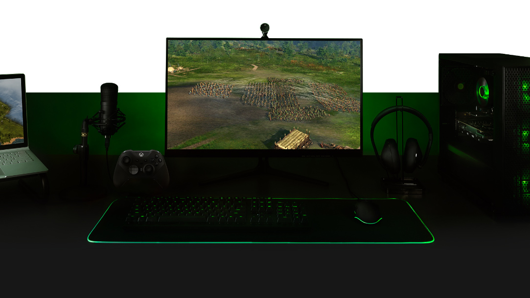 เดสก์ท็อปพร้อมพีซี, จอภาพที่มีหน้าจอเกม Ara: History Untold, คีย์บอร์ด, Xbox One Controller, ไมโครโฟน และแล็ปท็อปที่ติดตั้งไว้ด้วยกันทั้งหมด